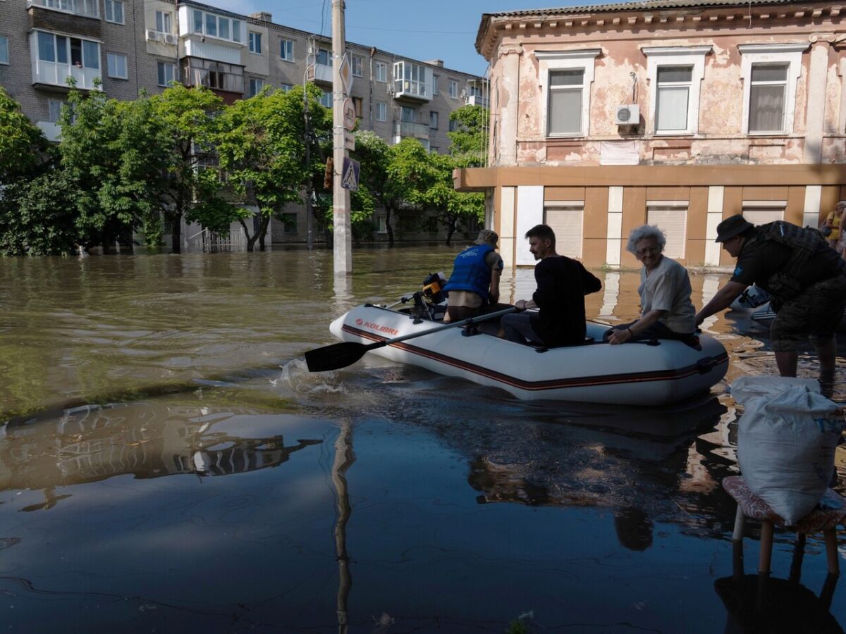 Militares ucranianos transportam um residente local em um barco durante uma evacuação de uma área inundada em Kherson