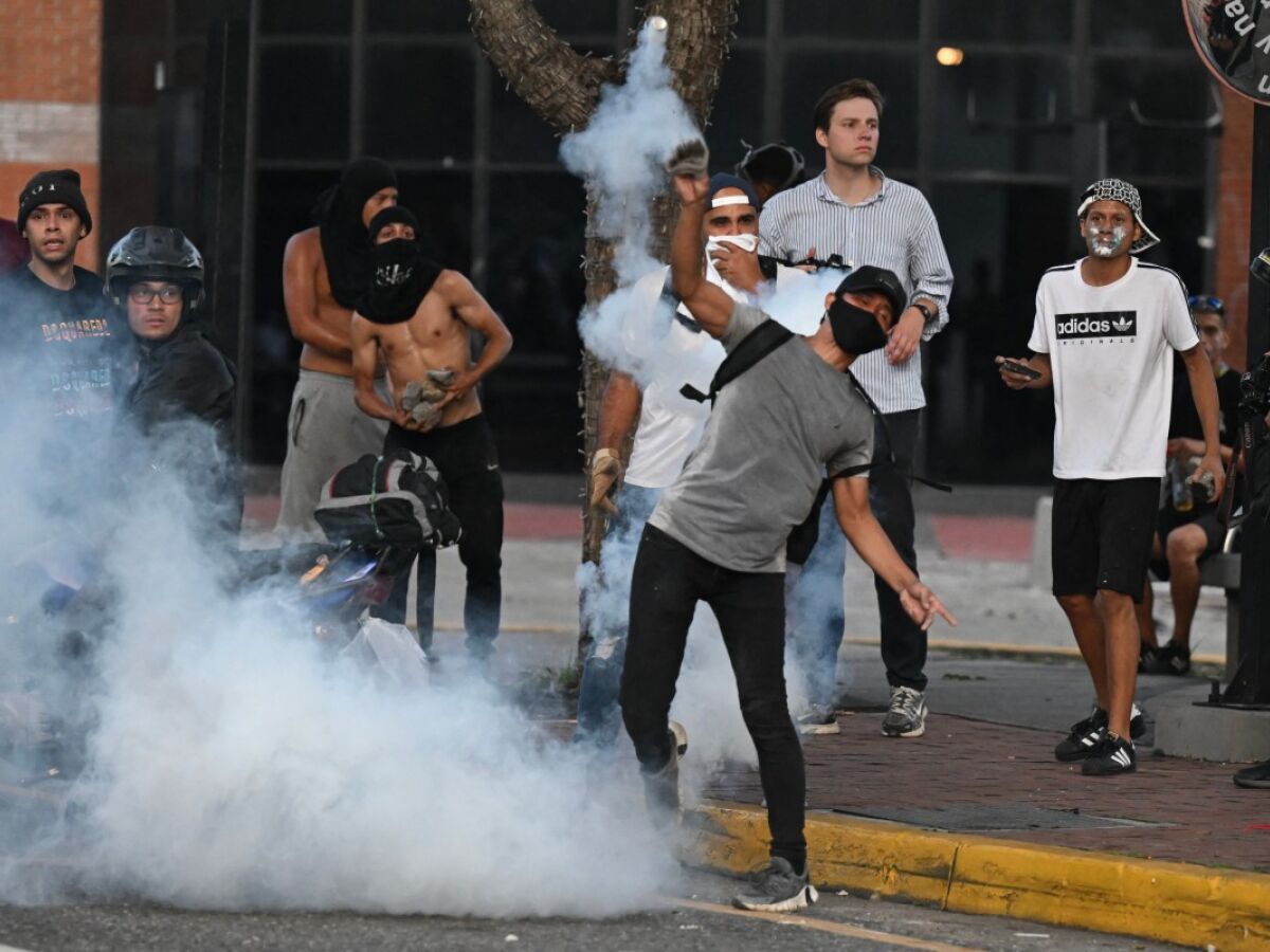 Um manifestante joga de volta para a polícia uma lata de gás lacrimogêneo durante um protesto contra o governo do presidente venezuelano Nicolás Maduro em Caracas 