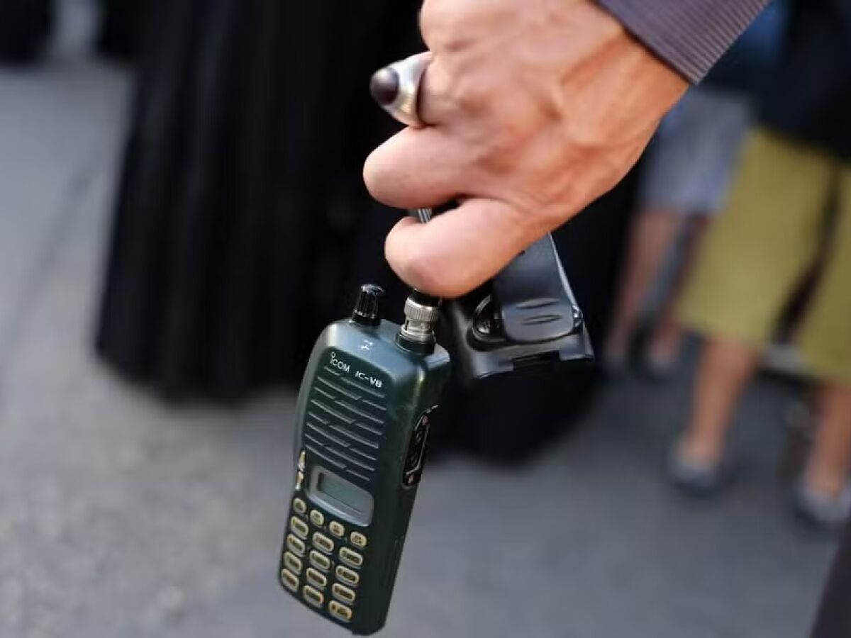 Homem segura walkie-talkie com a bateria removida durante o funeral de pessoas mortas na explosão de pagers, na terça-feira, no Líbano 