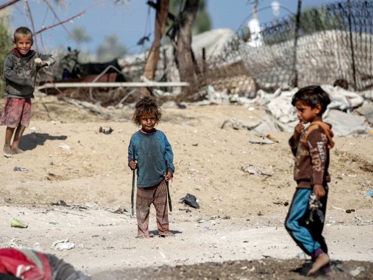 Crianças brincam juntas na poeira perto de barracos em Khan Yunis, no sul da Faixa de Gaza