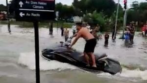 Em dia de chuvas fortes, dois homens andam de jet ski na avenida Recife