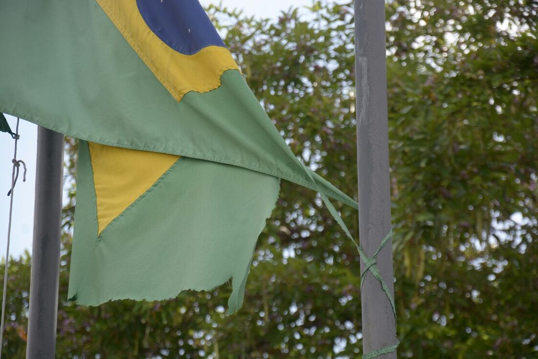 Bandeira do Brasil rasgada e amarrada a outro mastro