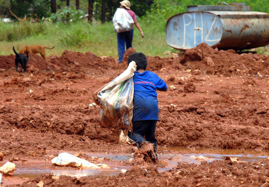 Criança saindo de lixão após coleta de recicláveis