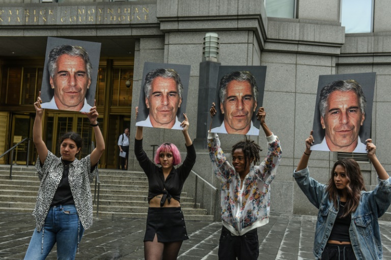 Manifestantes levantam cartazes ceom o rosto de Jeffrey Epstein enquanto o bilionário depõe em uma acusação de tráfico sexual de menores -