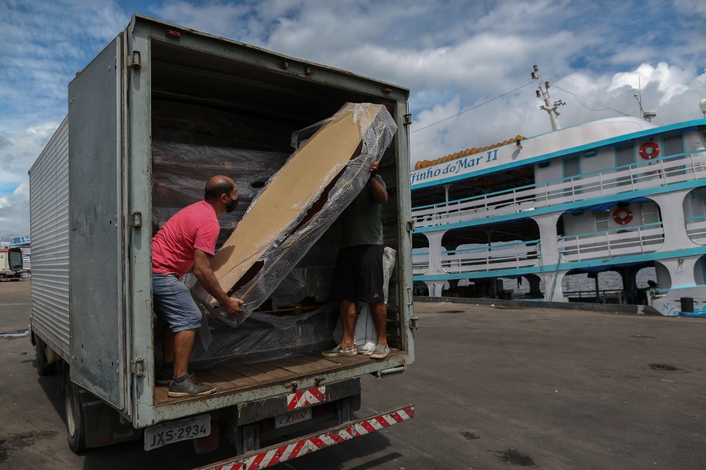 Homem retira caixões do caminhão, no Amazonas