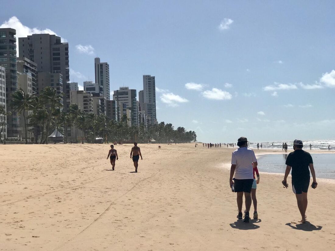 Pessoas caminhando na areia da praia de Boa Viagem