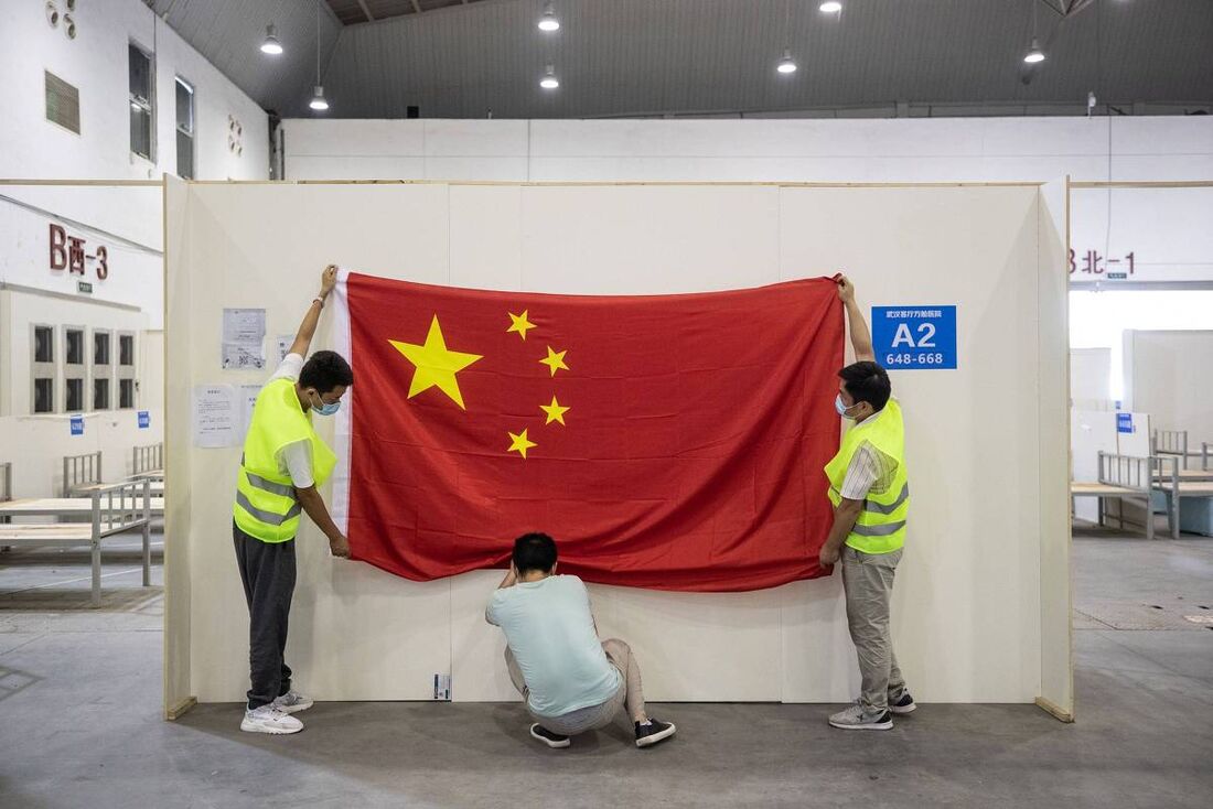 Trabalhadores com bandeira da China em hospital de campanha