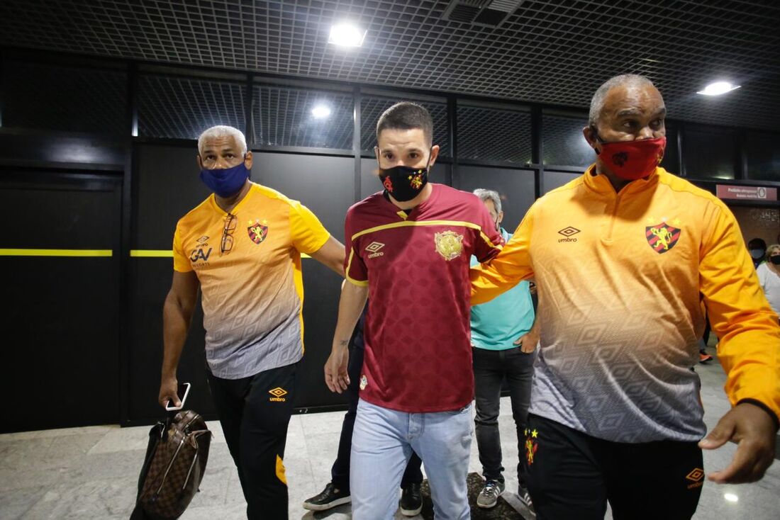 Thiago Neves é acompanhado por seguranças em desembarque no Recife