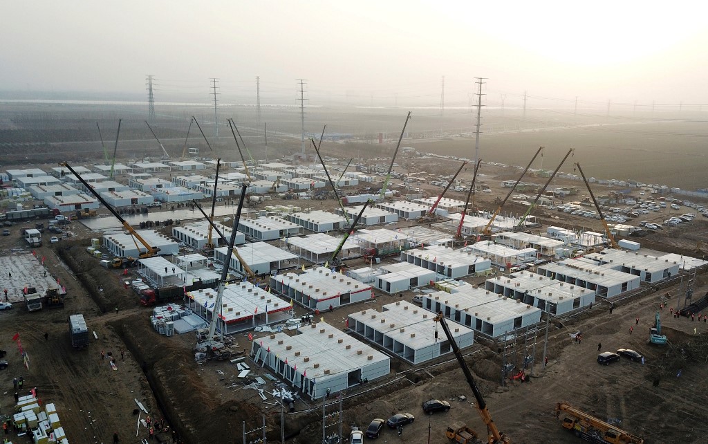 As equipes de construção civil trabalham dia e noite em um campo na periferia da cidade