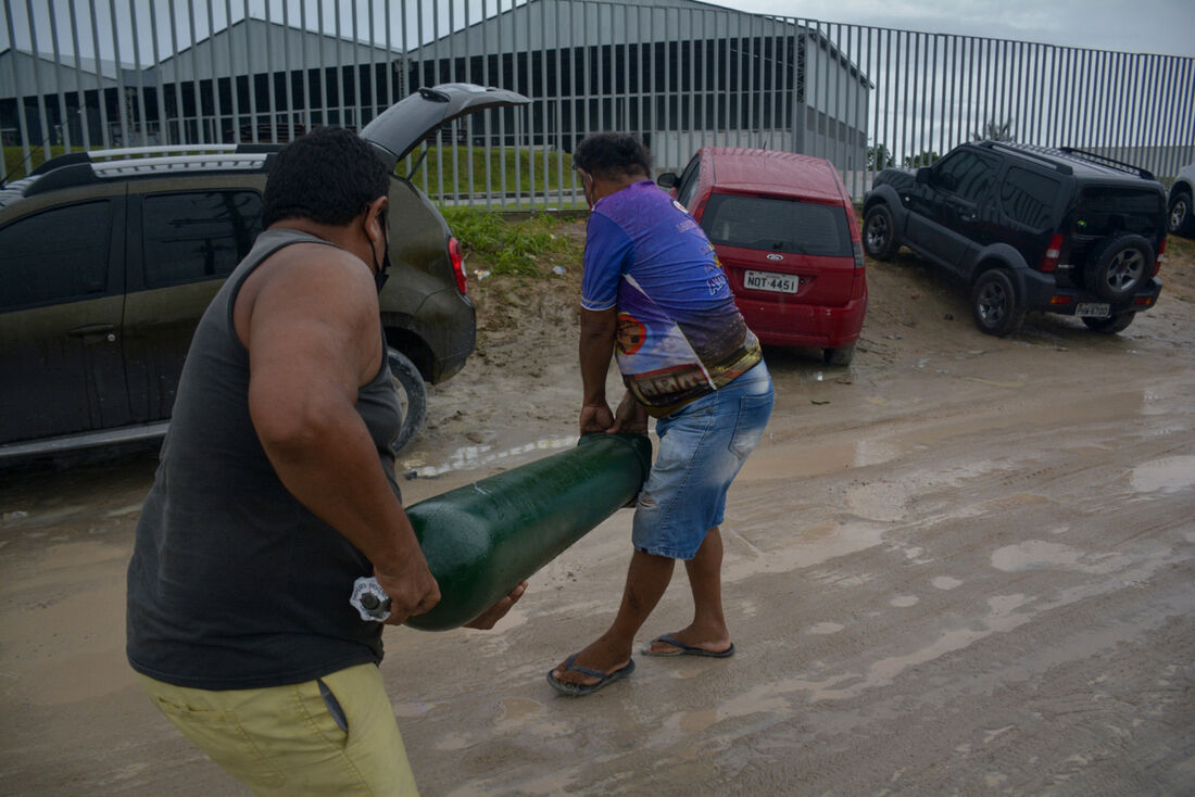 Parentes de pessoas internadas por Covid-19 carregando cilindros de oxigênio