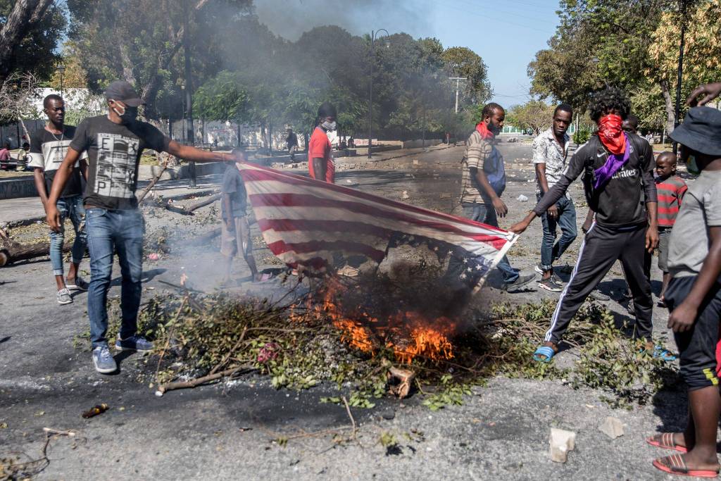 Manifestantes queimando uma bandeira americana, durante protesto pedindo a renúncia do presidente haitiano Jovenel Moïse