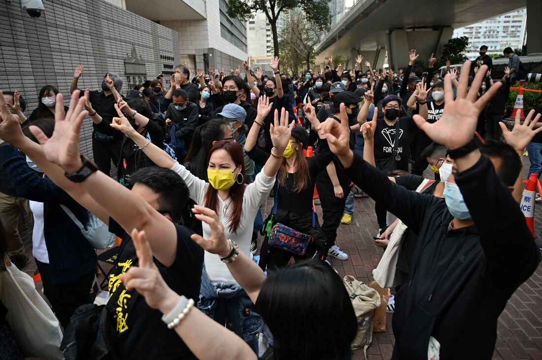 Apoiadores pró-democracia fazem sinais com as mãos do lado de fora do tribunal de West Kowloon em Hong Kong