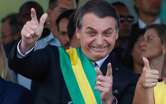 Bolsonaro fazendo sinal de arma com as mãos