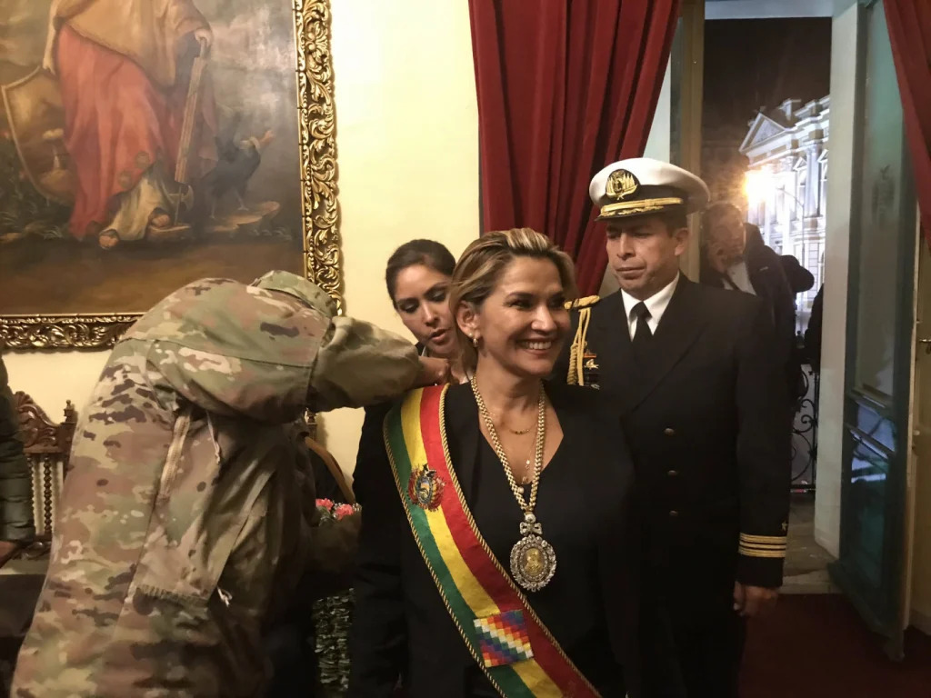 Militar ajeita faixa presidencial na presidente autodeclarada da Bolívia, Janine Aiñez, em 2019