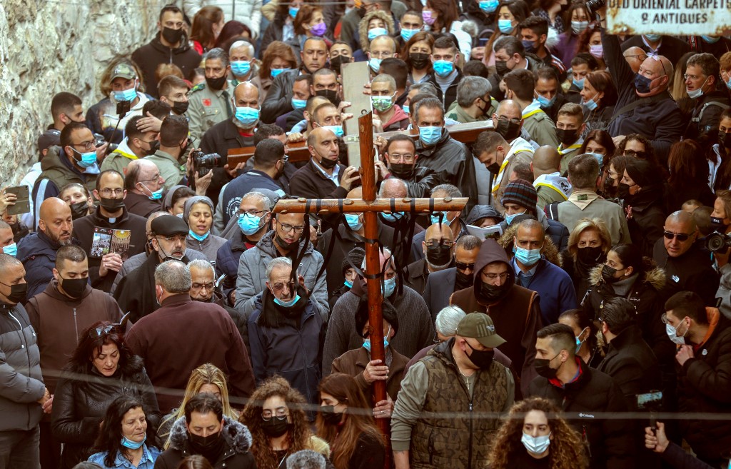 Adoradores cristãos carregam uma cruz de madeira ao longo da Via Dolorosa (Caminho do Sofrimento) na Cidade Velha de Jerusalém
