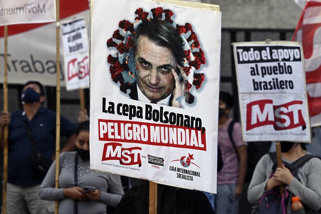 Pessoas seguram faixas representando o presidente do Brasil Jair Bolsonaro durante um protesto em frente à Embaixada do Brasil em Buenos Aires, no dia 14 de abril