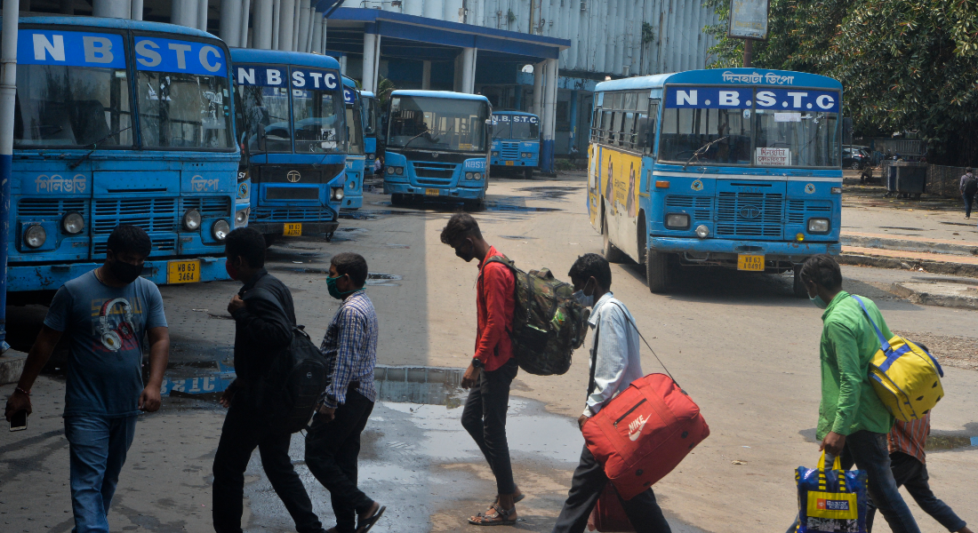 Passageiros caminham na estação da North Bengal State Transport Corporation após o anúncio do departamento de estado de West Bengal de serviços limitados de ônibus em meio à pandemia