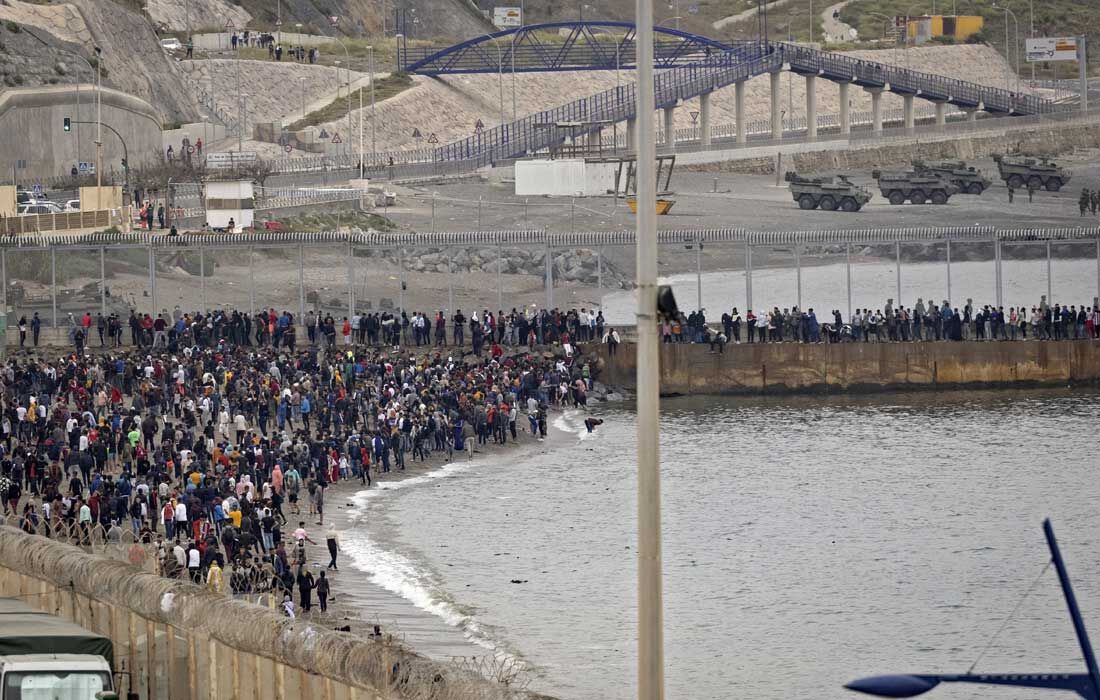 Migrantes marroquinos se reúnem perto de uma cerca de fronteira na cidade de Fnideq, no norte, na tentativa de cruzar a fronteira do Marrocos, enquanto as tropas espanholas tentam