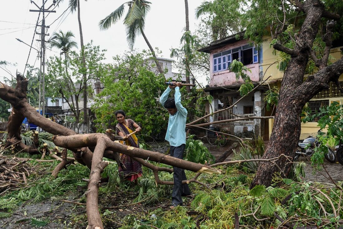 Moradores cortaram galhos de uma árvore caída em Mahuva, depois que o ciclone Tauktae