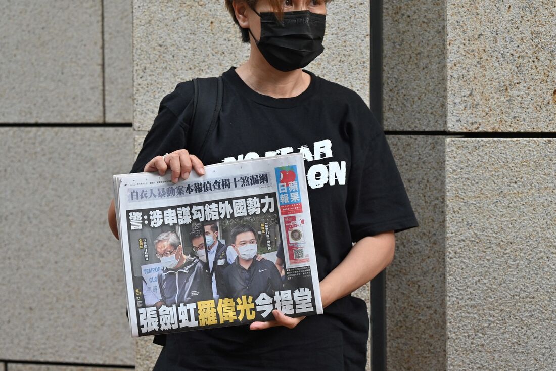 Um apoiador de do executivos do jornal pró-democracia Apple Daily de Hong Kong, o editor-chefe Ryan Law e o CEO Cheung Kim-hung, segurando um exemplar do jornal durante um protesto fora do tribunal em Hong Kong em 19 de junho de 2021, após os dois serem a