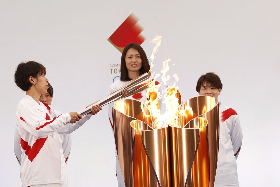 A portadora da tocha japonesa Azusa Iwashimizu, membro da seleção nacional feminina de futebol do Japão, acende a tocha olímpica no primeiro dia do revezamento da tocha