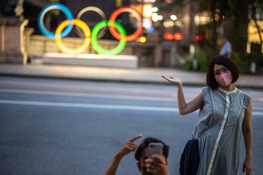 Casal posa em frente aos anéis olímpicos de Tóquio, no distrito de Nihonbashi