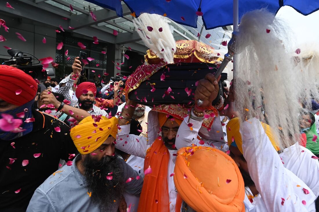 Homens carregam o Guru Granth Sahib, que foi trazido do Afeganistão após a tomada pelo Talibã