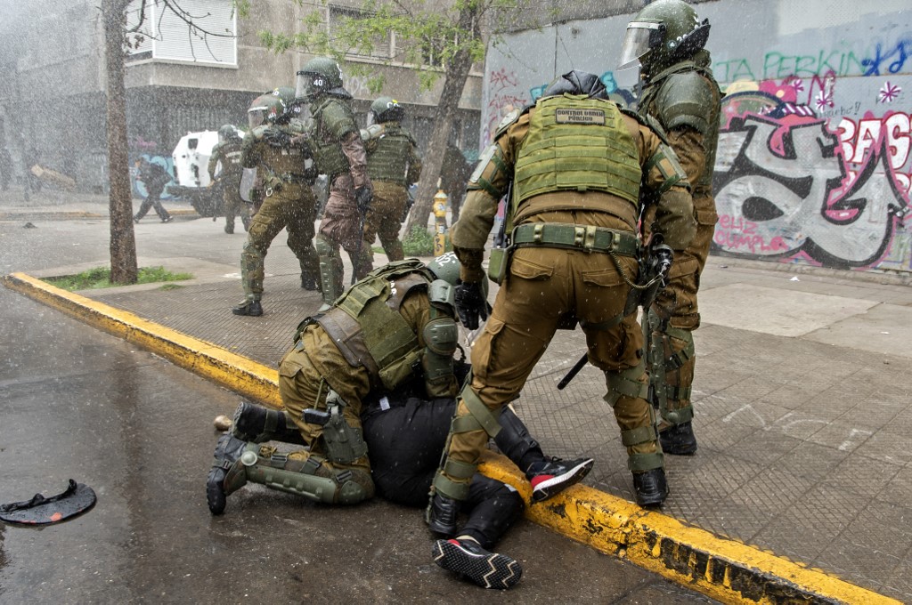 Policiais prendendo um manifestante nos protesto a favor do povo mapuche em Santiago, no Chile