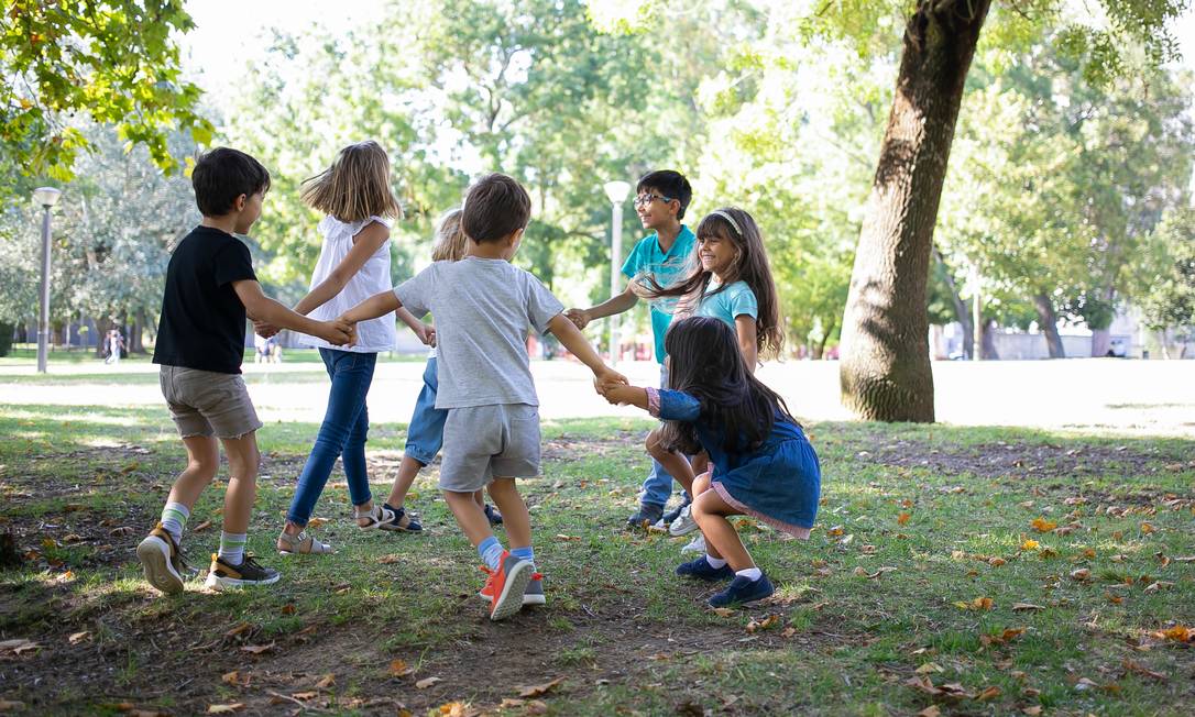 Crianças brincam em roda num parque 