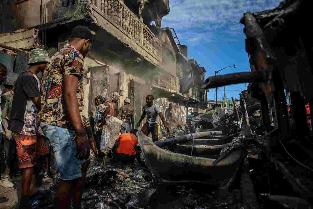 Homens pegam pedaços de alumínio no local onde um caminhão-tanque explodiu em Cap-Haitien, Haiti, em 14 de dezembro de 2021