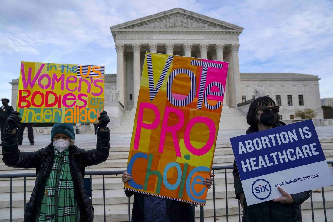 Os participantes seguram cartazes durante a Marcha das Mulheres "Hold The Line For Abortion Justice" na Suprema Corte dos EUA em 01 de dezembro de 2021 em Washington, DC