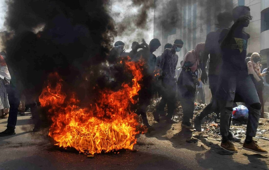 Manifestantes sudaneses se manifestam contra os militares, passando por pneus em chamas na capital Cartum, em 6 de janeiro de 2022