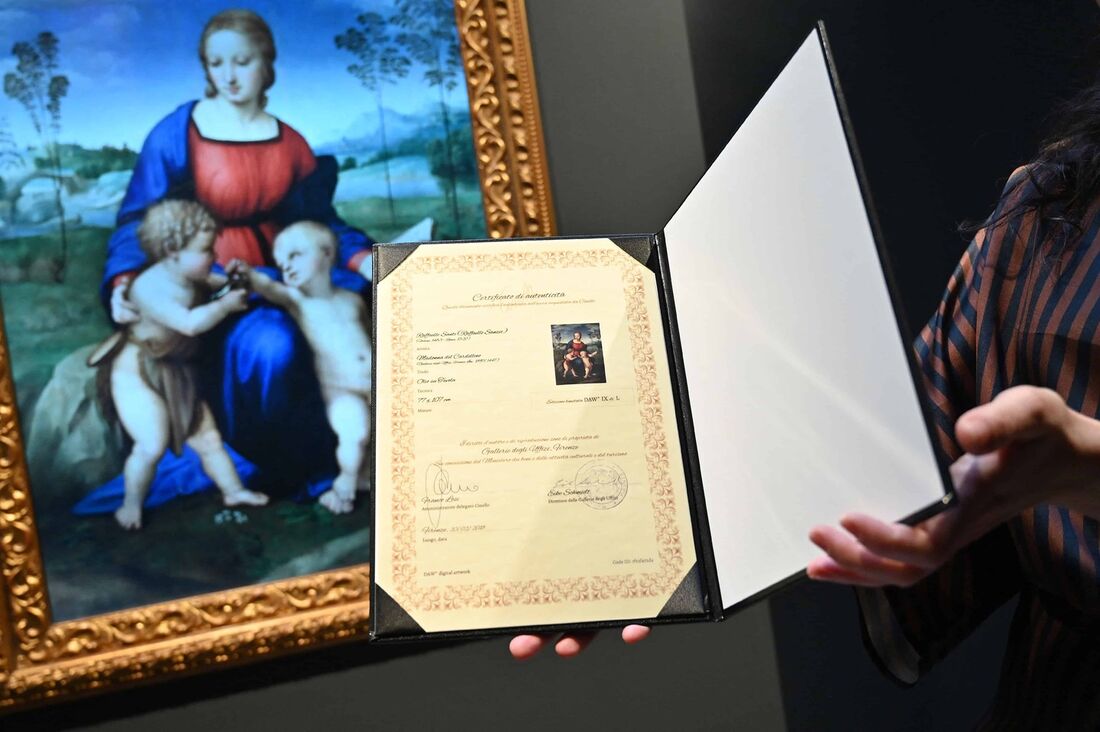 Um assistente de galeria observa uma reprodução digital da pintura 'Madonna del Cardellino (Madonna of the Goldfinch' de Raphael, exibida como parte da exposição 'Eternalising Art History: From Da Vinci to Modigliani' na galeria Unit London em Londres