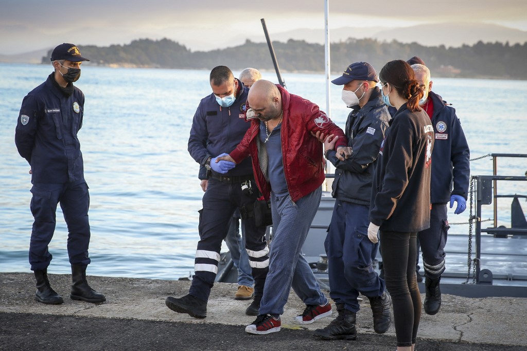 Um passageiro é ajudado a sair do Euroferry Olympia por equipes de resgate e oficiais da guarda costeira ao chegar ao porto de Corfu, em 18 de fevereiro de 2022