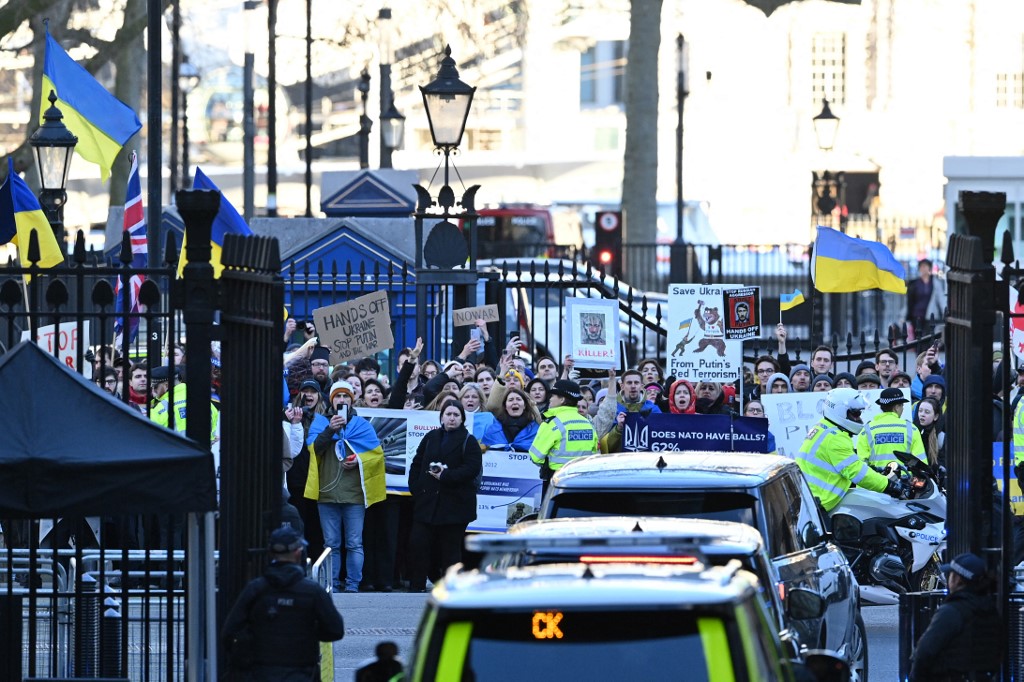 Manifestantes com bandeiras ucranianas cumprimentam o primeiro-ministro britânico Boris Johnson quando ele sai da 10 Downing Street, no centro de Londres, em 24 de fevereiro de 2022, para fazer uma declaração aos parlamentares nas Casas do Parlamento sobr