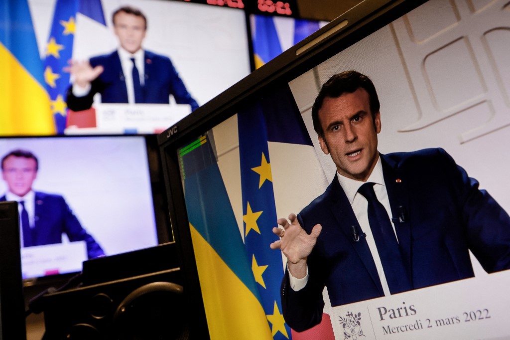 Uma foto de monitores tirada em uma sala de controle de mídia em Paris em 2 de março de 2022 mostra o presidente francês Emmanuel Macron falando do Palácio do Eliseu durante um discurso televisionado sobre a situação geral sete dias depois que a Rússia la