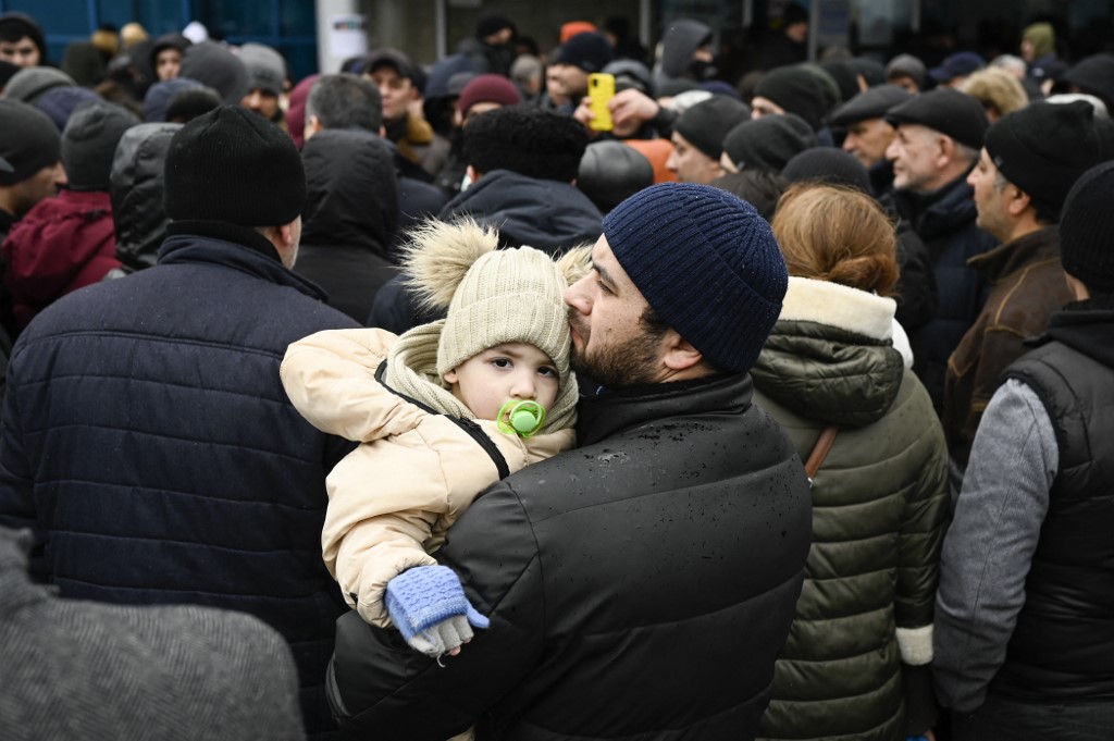 Um homem segura seu filho enquanto as famílias, que fugiram da Ucrânia devido à invasão russa, esperam para entrar em um campo de refugiados na capital da Moldávia, Chisinau, em 3 de março de 2022