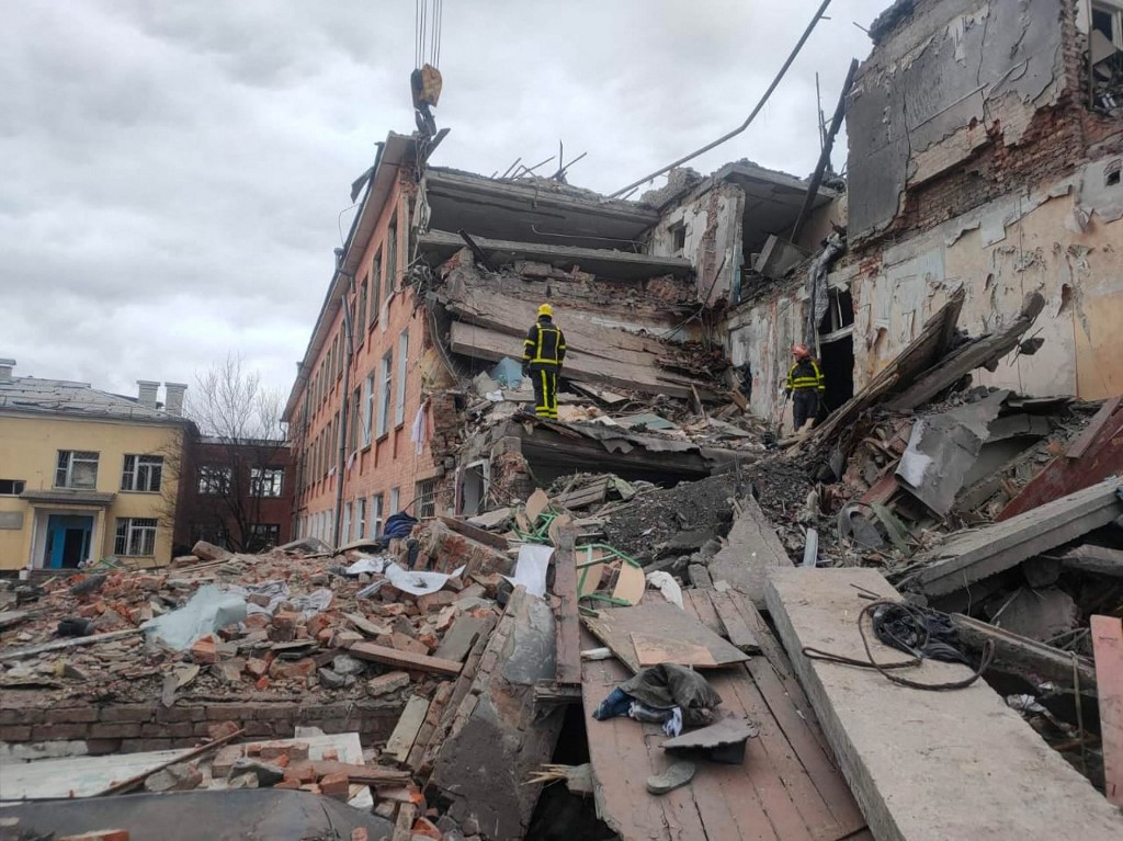 Equipes de resgate desmantelando os escombros de uma escola destruída depois que tropas russas bombardearam a cidade de Chernihiv