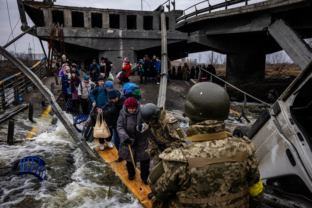 vacuados atravessam uma ponte destruída enquanto fogem da cidade de Irpin, a noroeste de Kiev, em 7 de março de 2022