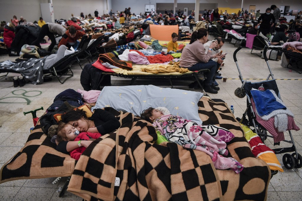 Uma mãe dorme com seus filhos entre muitos outros em um abrigo temporário que hospeda os refugiados ucranianos localizado em um antigo shopping center perto da cidade de Przemysl, em 08 de março de 2022