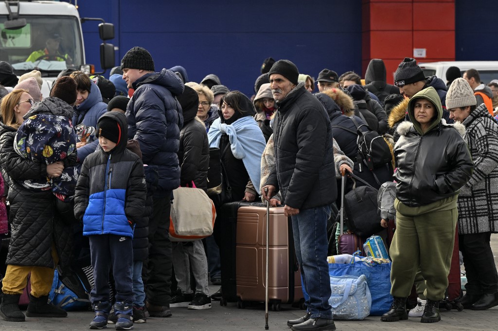 Pessoas ficam com suas bagagens enquanto esperam ser realocadas do abrigo temporário para refugiados em um antigo shopping center entre a fronteira ucraniana e a cidade polonesa de Przemysl, na Polônia, em 8 de março de 2022