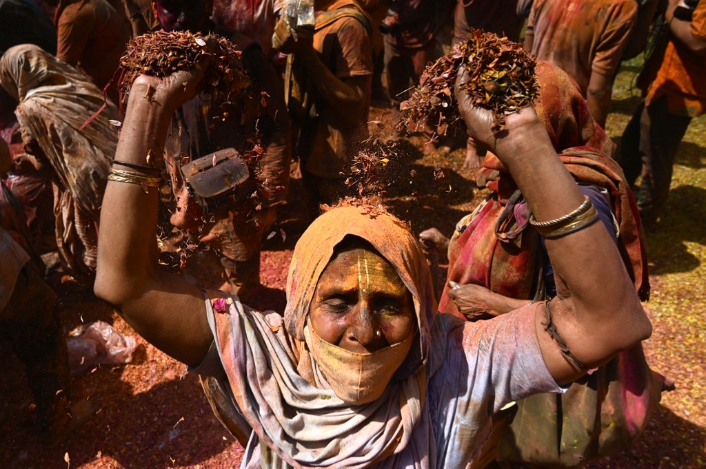 Uma viúva manchada com Gulal (pó de cor) dança enquanto participa das celebrações do Holi, o festival de cores da primavera hindu, em um templo em Vrindavan em 15 de março de 2022