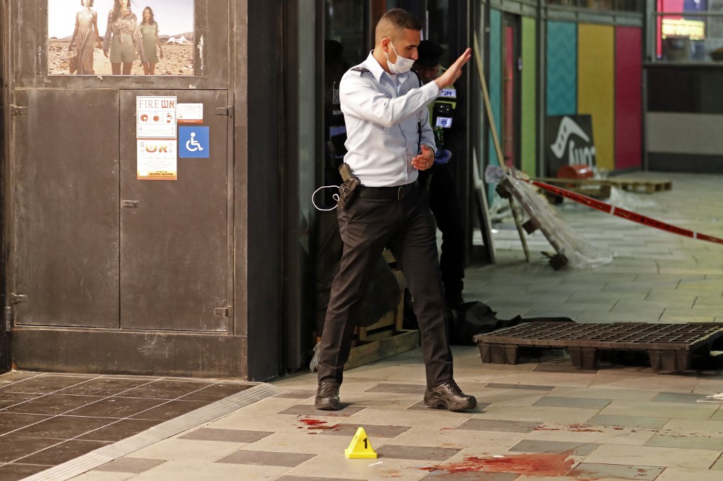 Um policial gesticula perto de manchas de sangue no local de um ataque com faca do lado de fora de um shopping na cidade de Beersheba, no sul de Israel, em 22 de março de 2022