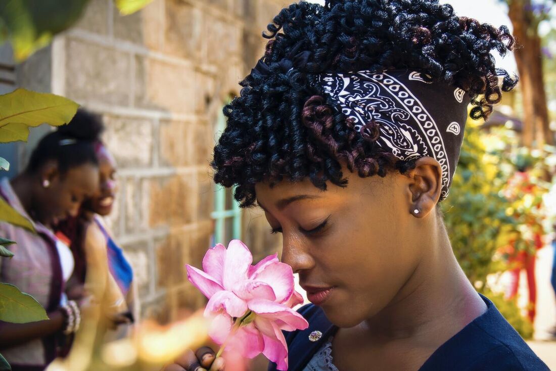 Mulher segura e cheira uma rosa