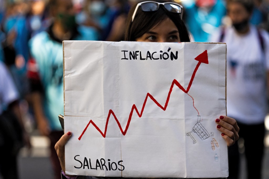 Uma mulher segura uma placa com os dizeres "Inflação" e "Salários" durante um protesto de organizações sociais exigindo mais ajuda do governo, em Buenos Aires, em 13 de abril de 2022