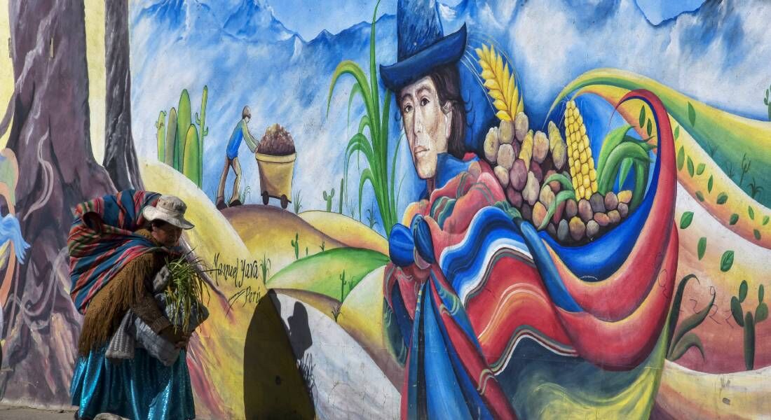 Uma indígena aimara caminha por um mural em El Alto, Bolívia, em 19 de abril 