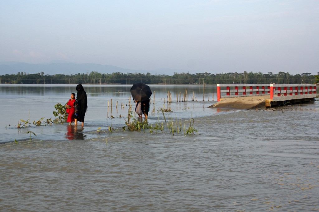 Pessoas atravessam uma estrada inundada após fortes chuvas em Sylhet em 23 de maio de 2022. Pelo menos quatro milhões de pessoas foram afetadas pelas piores inundações no nordeste de Bangladesh em quase duas décadas