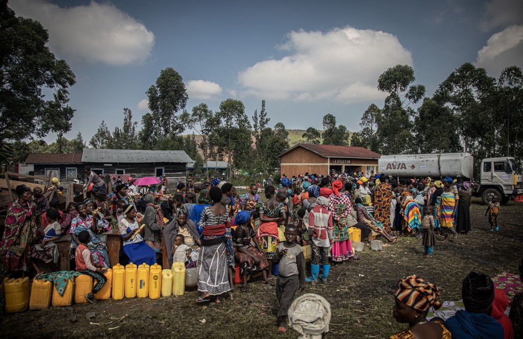 Deslocados internos, fugindo dos recentes confrontos entre rebeldes do M23 e soldados congoleses, fazem fila para coletar água de um tanque de água em Kanyarushinya, ao norte de Goma, em 27 de maio de 2022