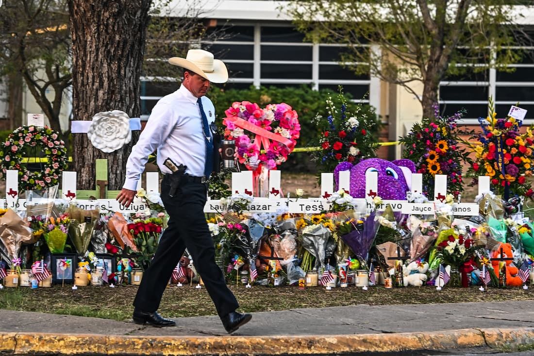 Policial caminha pelo memorial feito para as vítimas na escola Uvalde, nos Estados Unidos