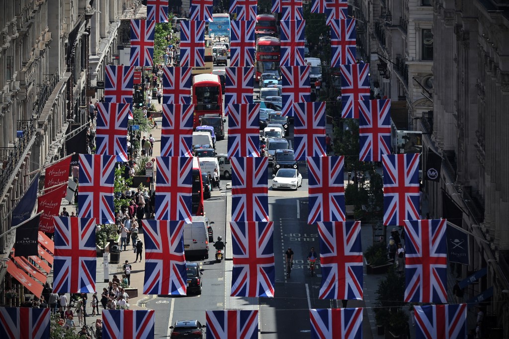 Os ônibus e o tráfego vermelhos de Londres passam sob as bandeiras da União, colocadas para celebrar o Jubileu de Platina da rainha Elizabeth, na Regent Street, no centro de Londres, em 27 de maio de 2022